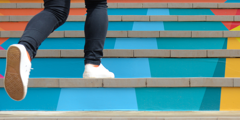 A person walking up colorful stairs